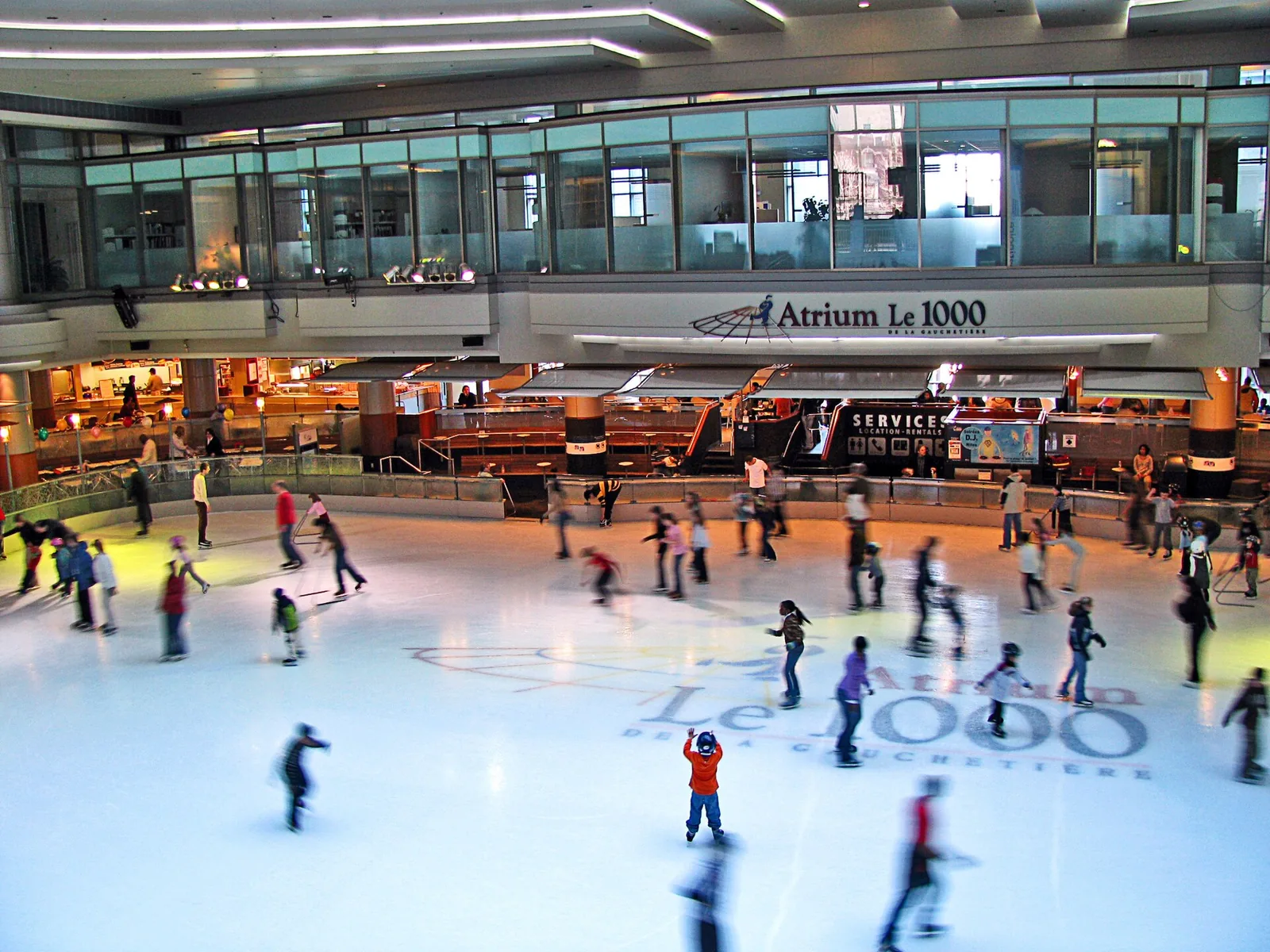 Skaters circling the indoor rink under the glass roof of Atrium Le 1000 in downtown Montreal