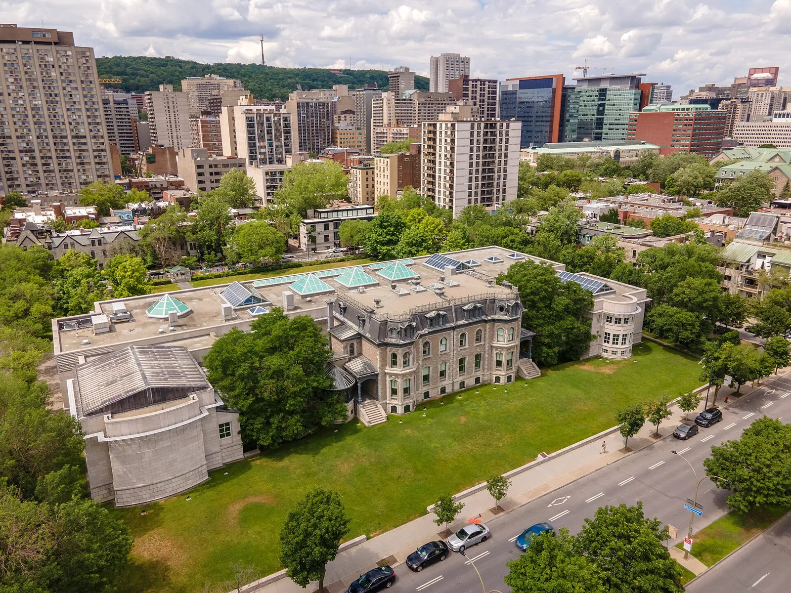 Aerial view of the Canadian Centre for Architecture building and its lawns with downtown Montreal and Mount Royal behind