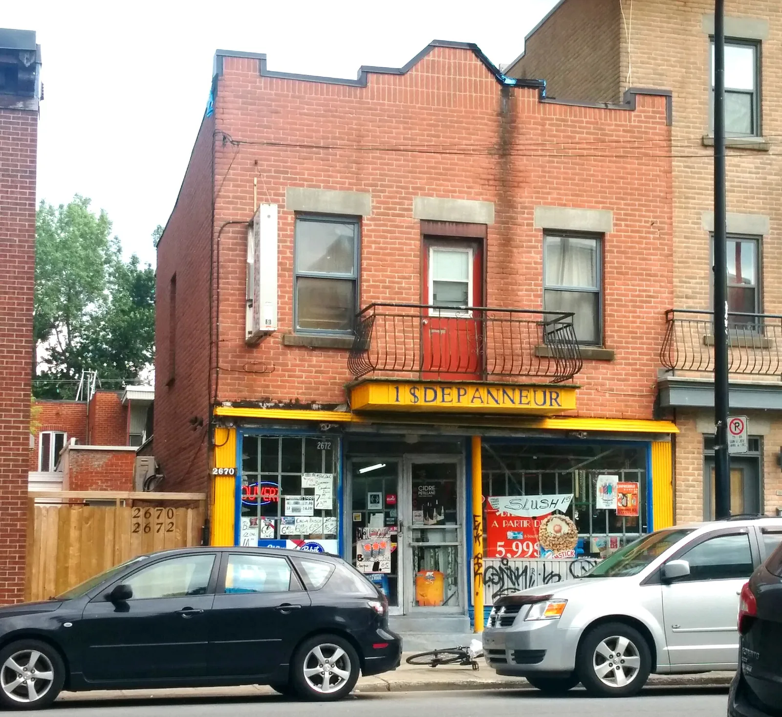 A red brick corner shop with a yellow Dépanneur sign on a Montreal street