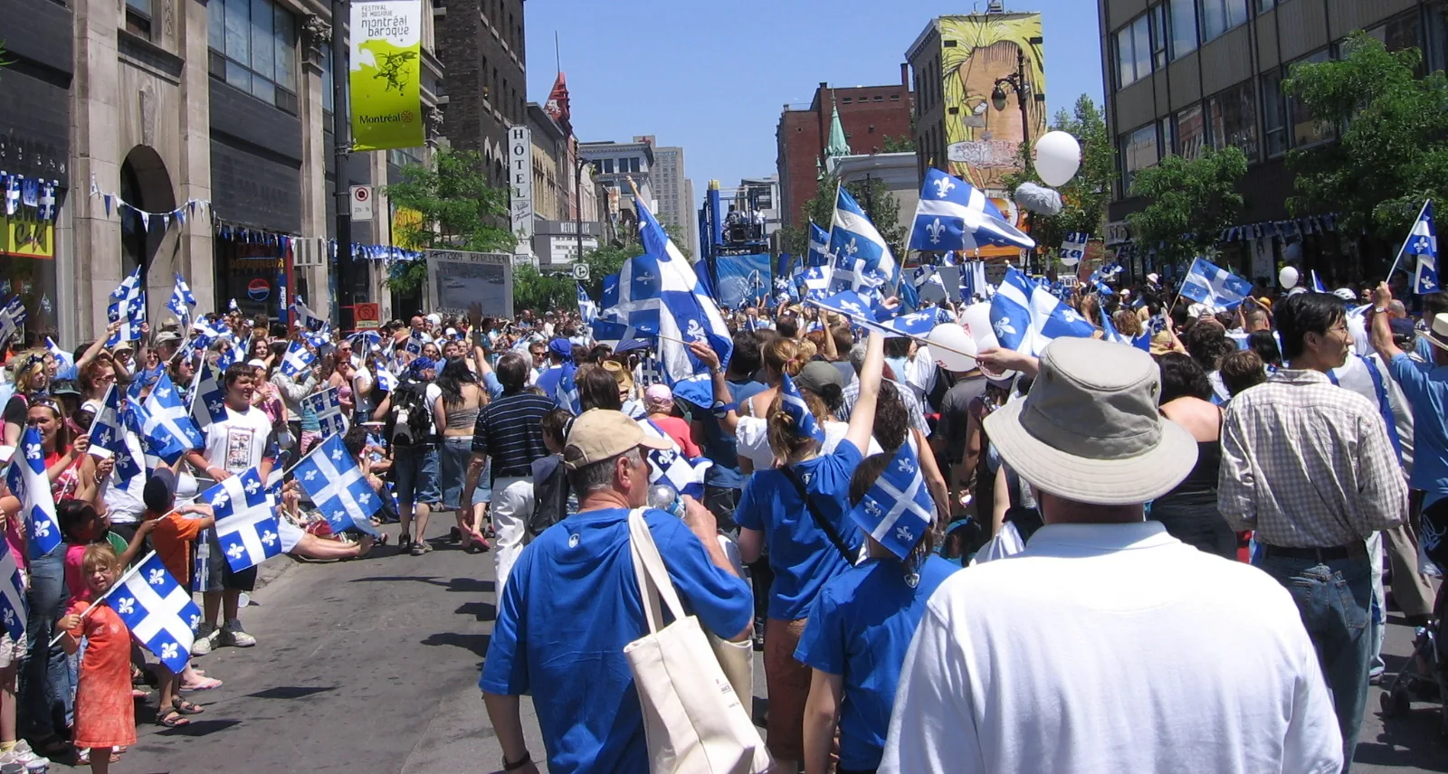 Crowd waving blue-and-white Quebec flags in a Montreal street on the Fête nationale, 24 June