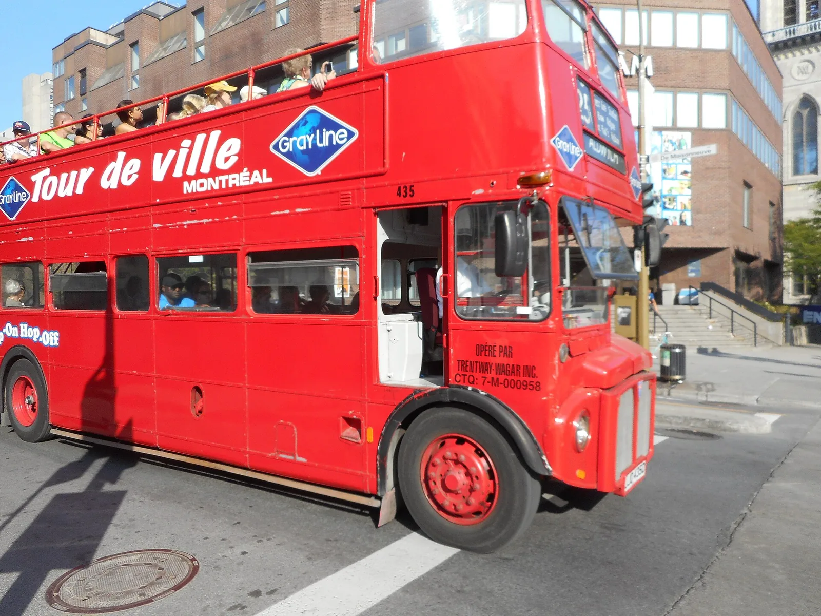 A red open-top Gray Line double-decker sightseeing bus on a Montreal street