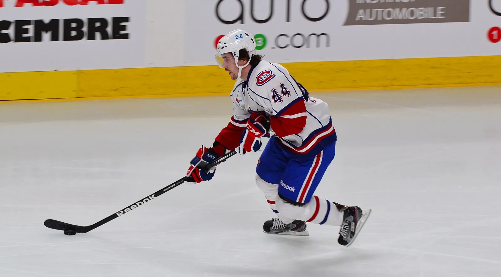 A player in a red, white and blue jersey skating with the puck during a game on the Bell Centre ice