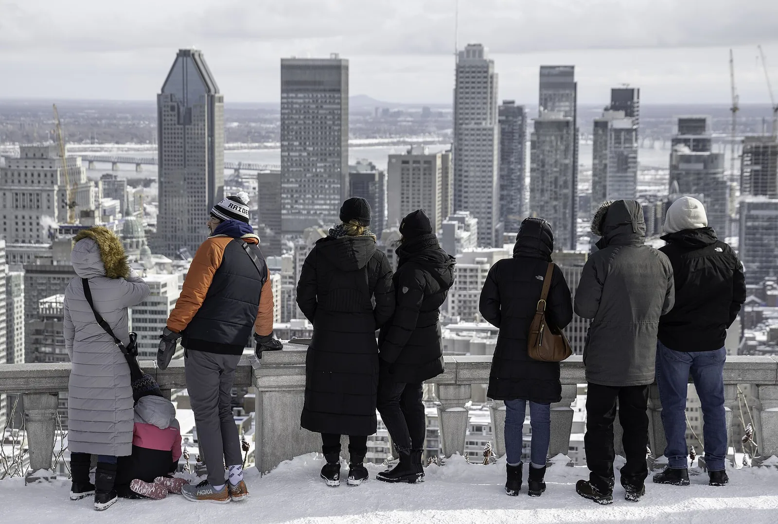 Visitors in winter coats looking over snowy downtown Montreal from the Kondiaronk Belvedere, typical Montreal weather in January
