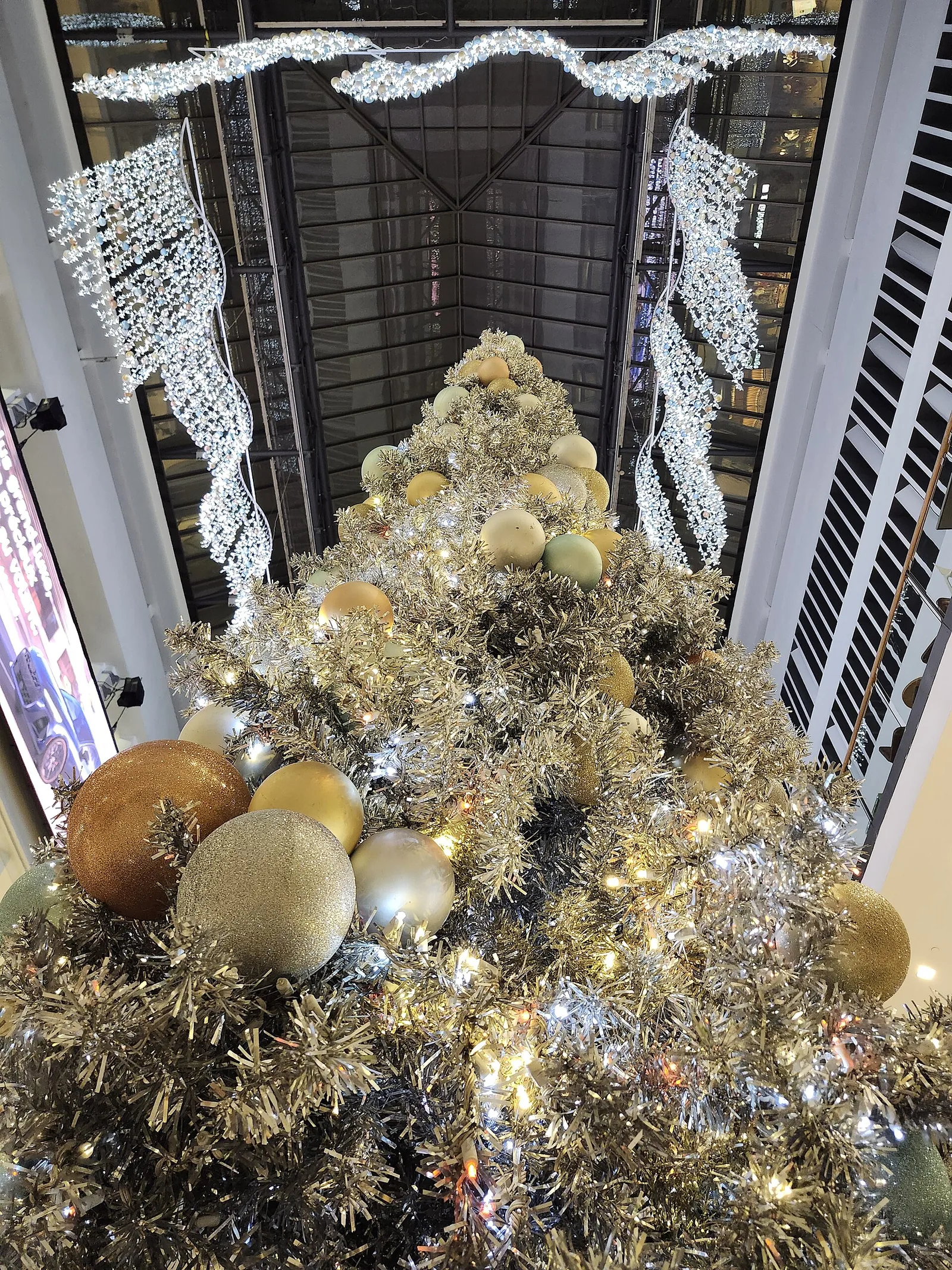 Looking down on a tall decorated Christmas tree and garlands of lights in a shopping-centre atrium