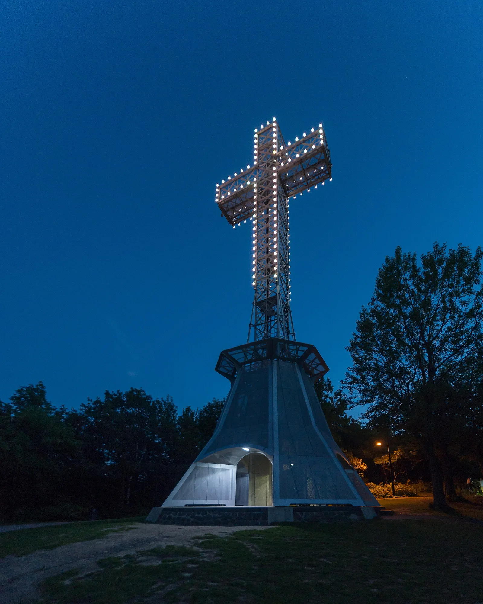 The illuminated steel Mount Royal Cross lit up against a deep blue evening sky