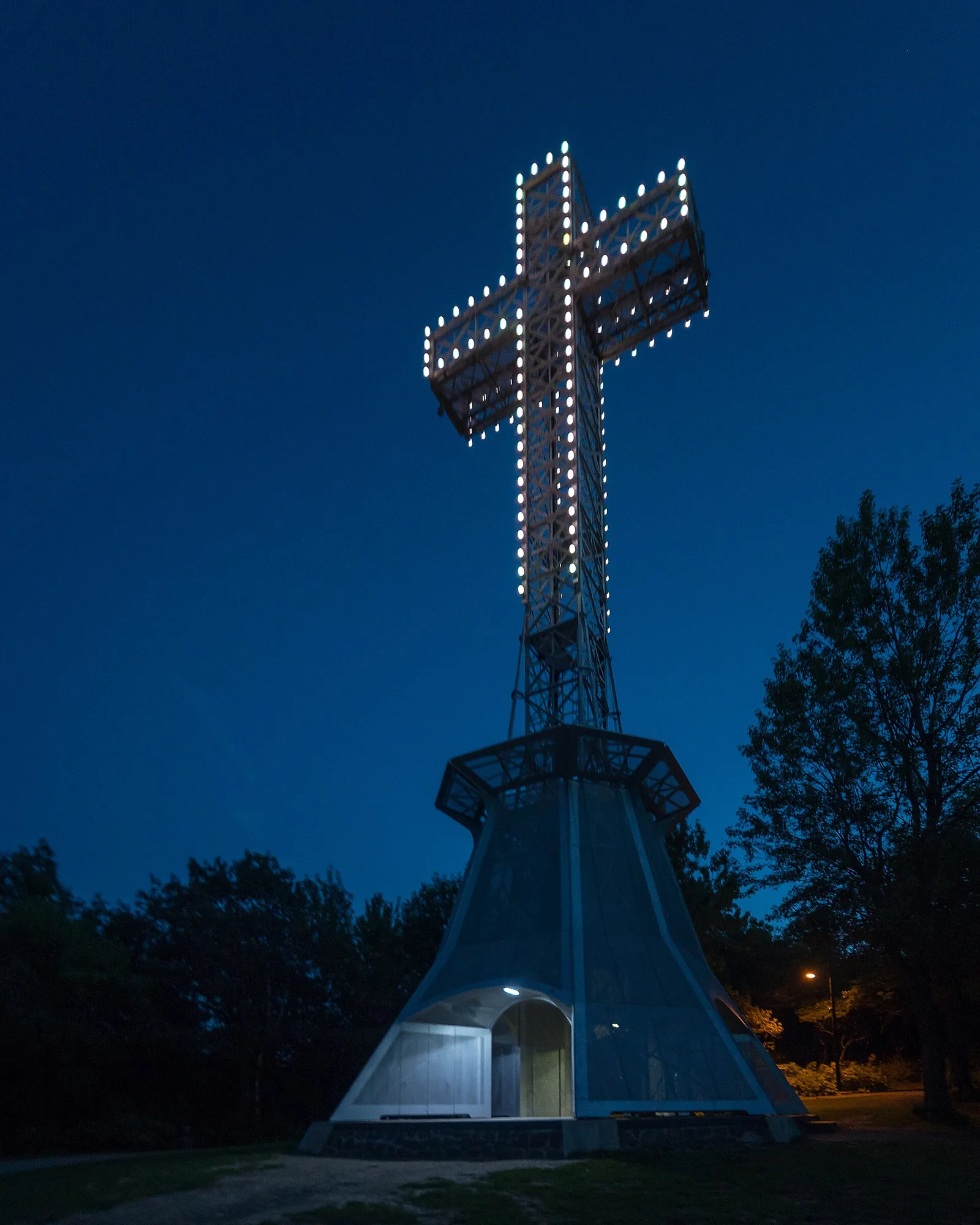 The illuminated Mount Royal Cross against a deep blue sky at dusk