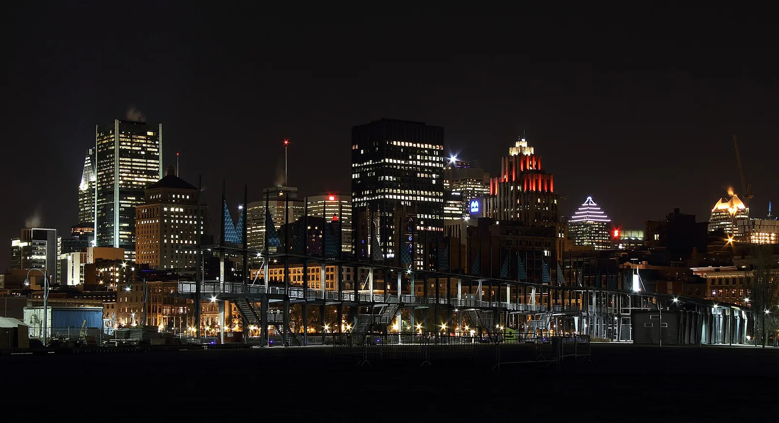 Downtown Montreal skyline lit up at night, seen across the water from the Old Port quays near Bota Bota