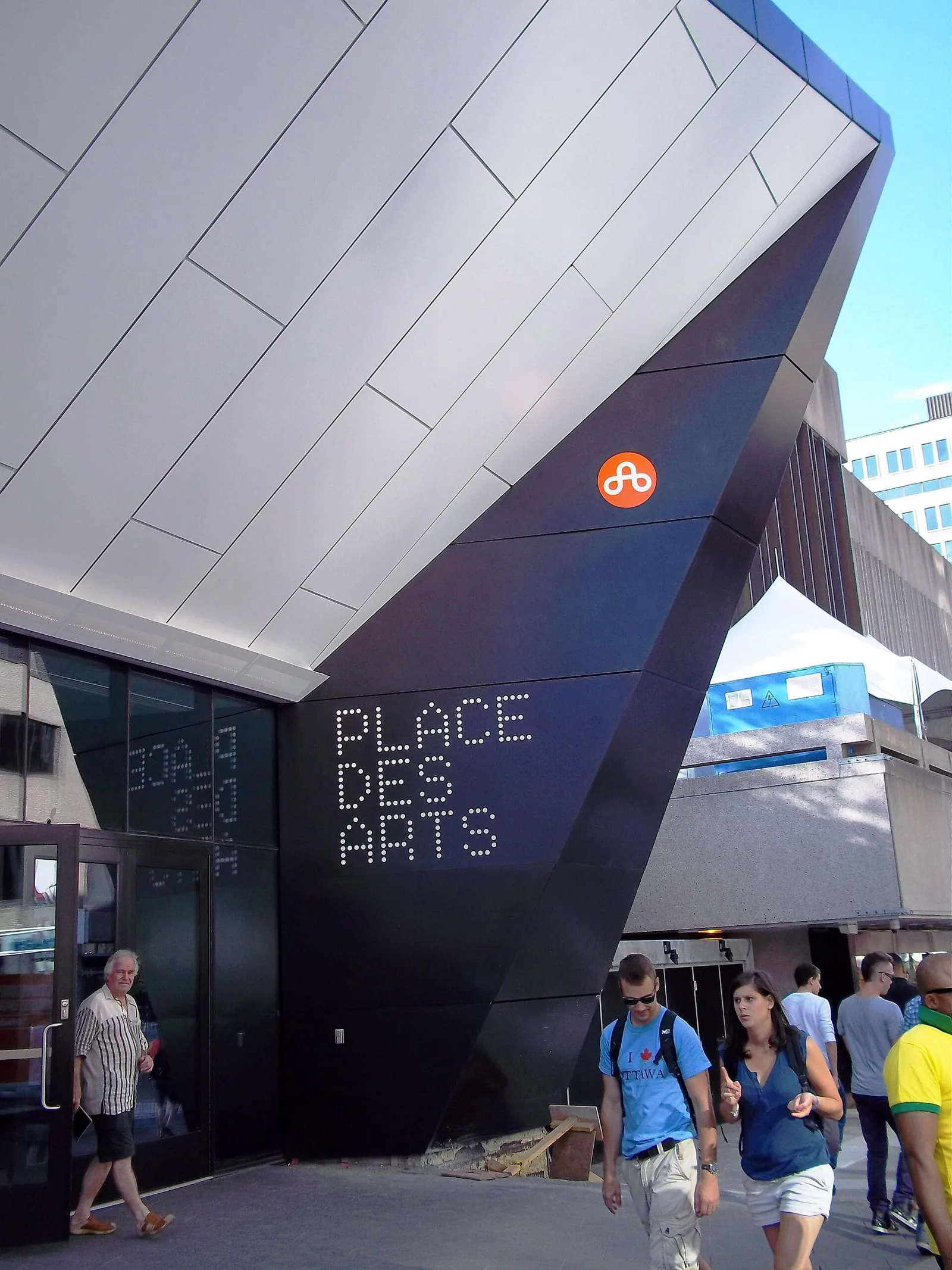 Visitors walking into the angular modern entrance of Place des Arts in the Quartier des Spectacles