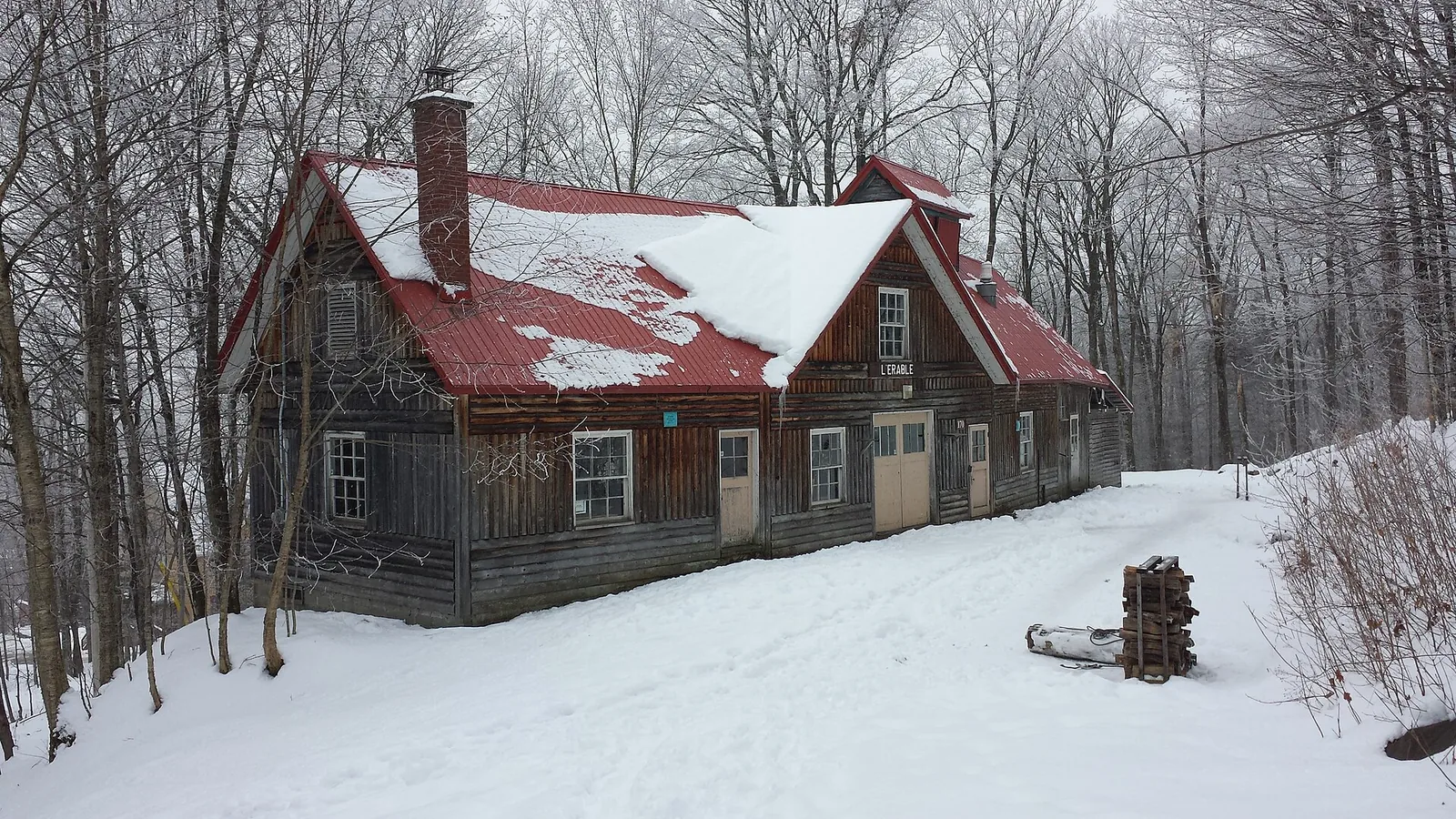 A red-roofed wooden sugar shack in the snow in the Quebec countryside