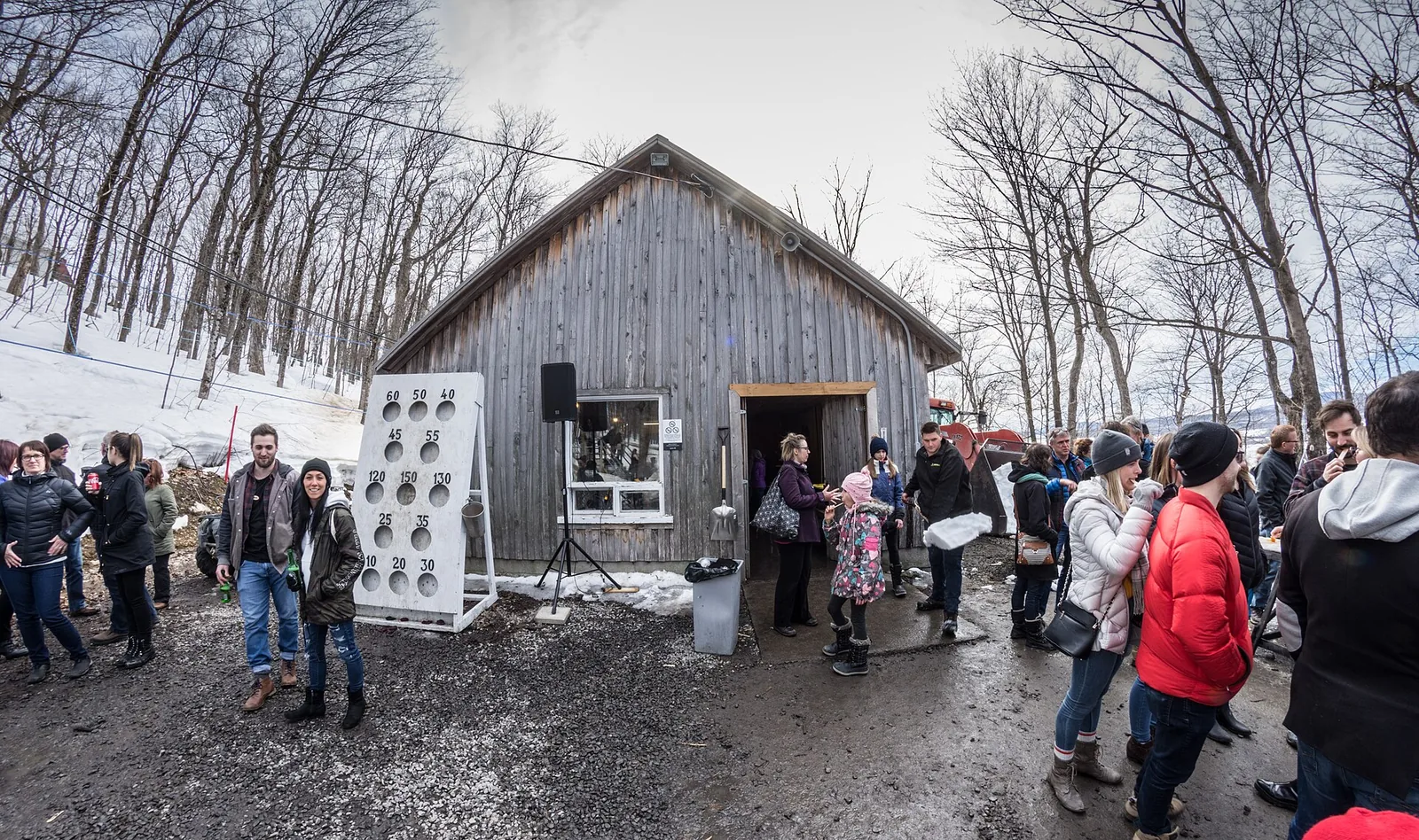 Families in winter coats queuing outside a wooden sugar shack in the Quebec snow