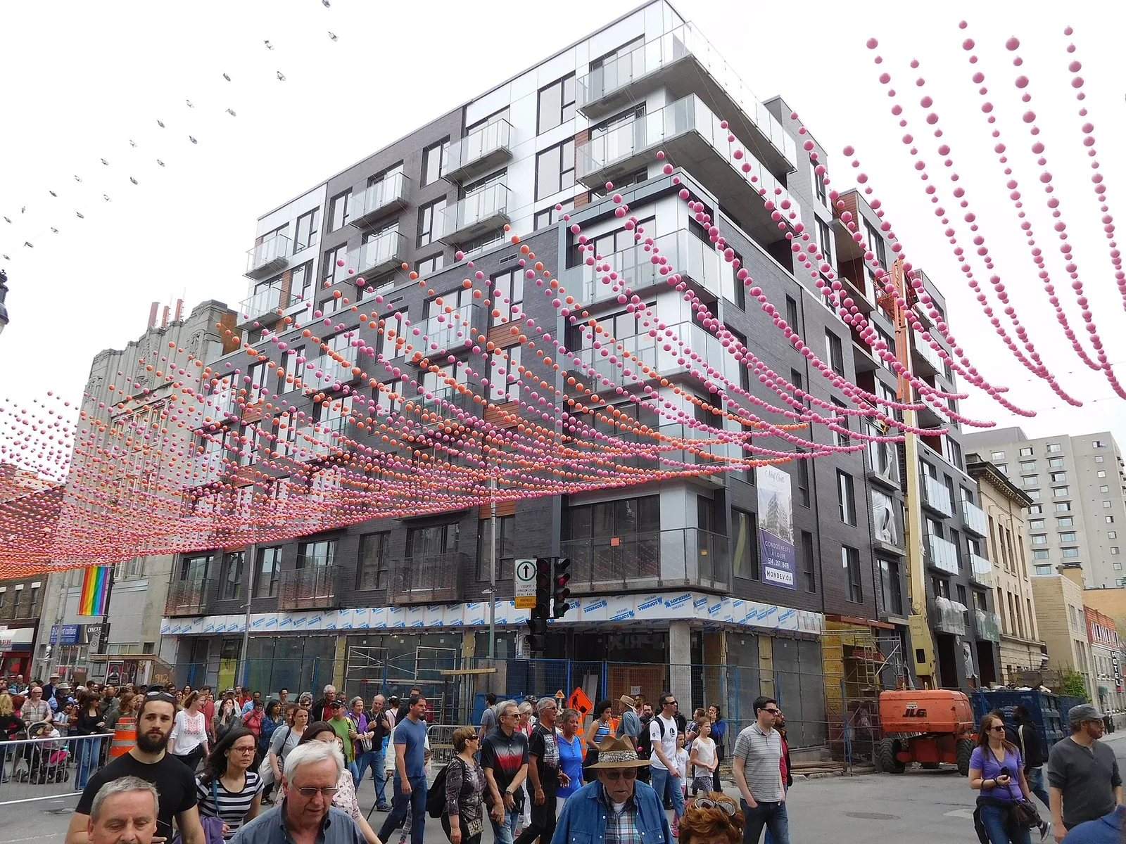 Crowds walking on a pedestrianised rue Sainte-Catherine Est in the Village under strings of overhead decorations