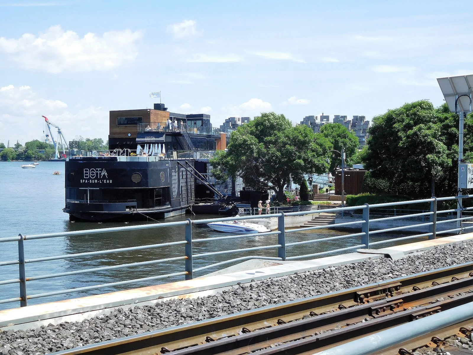 Bota Bota spa Montreal seen from the Old Port waterfront path, a converted black ferry moored beside the quay
